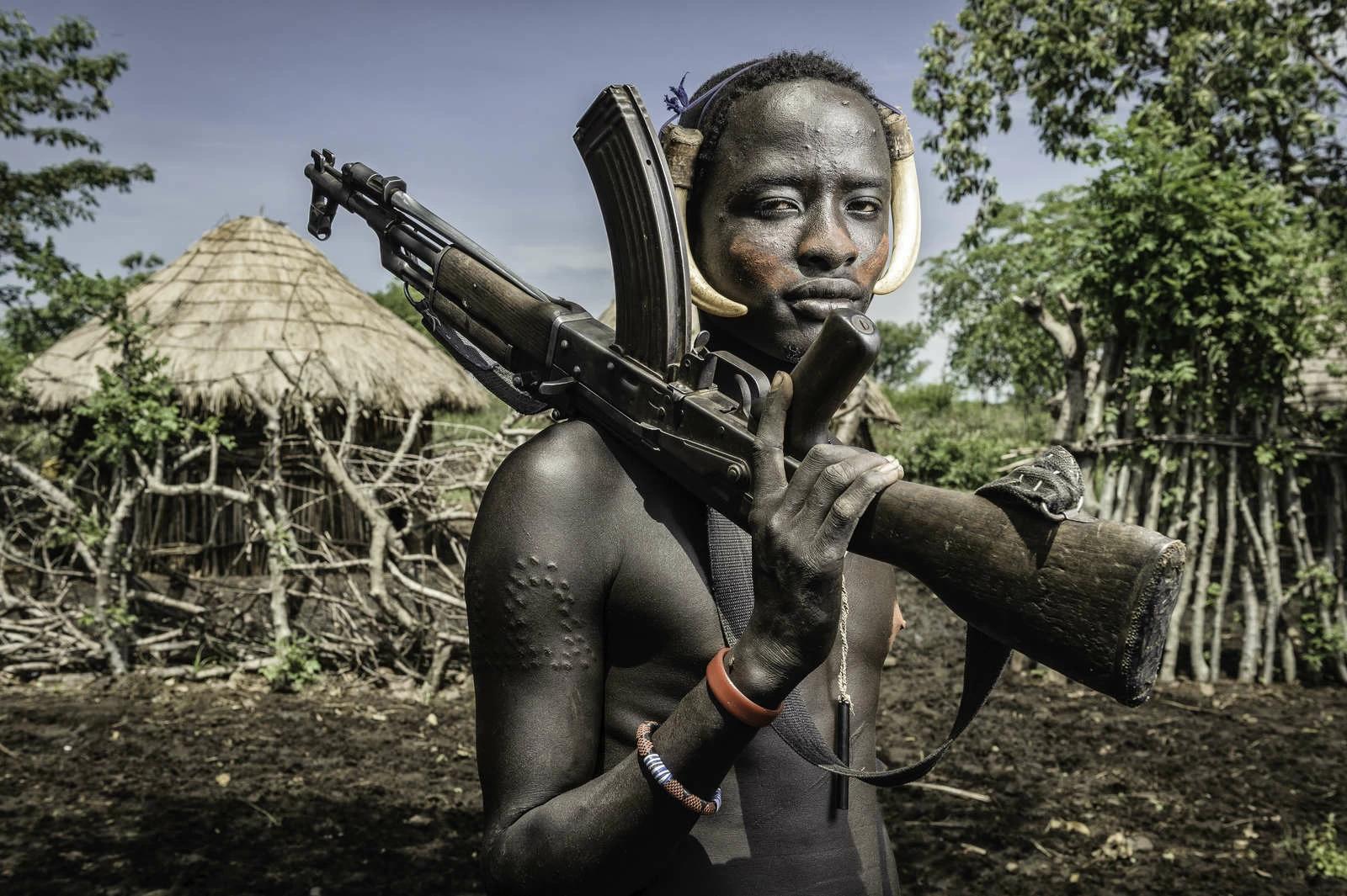 Portrait of a young Mursi man holding a Kalashnikov. Photo and story by Jorge Fernandez