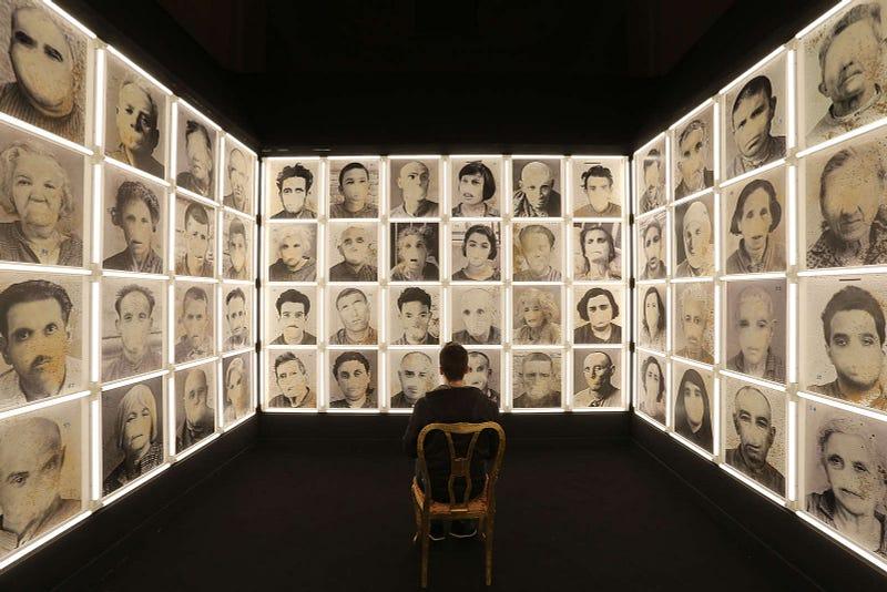 A man sitting in the middle of a room in an installation depicting madmen without a mouth, in the museum of madness. Photo and story by Marco Cantile